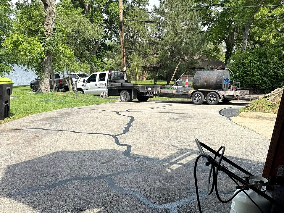 Crack filling in progress — fresh sealant filling the cracks with the work truck and tank rig behind