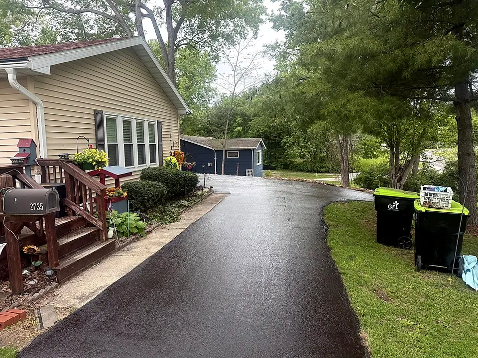 A curving wet-black residential driveway after seal coating