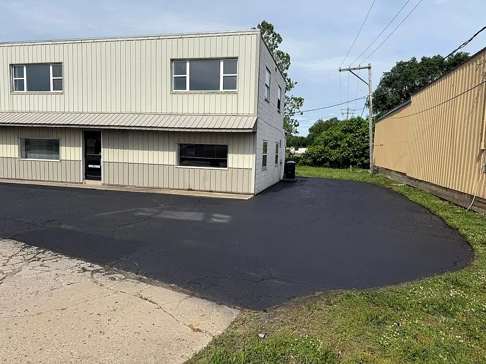 Deep wet-black sealed lot wrapping around a commercial building