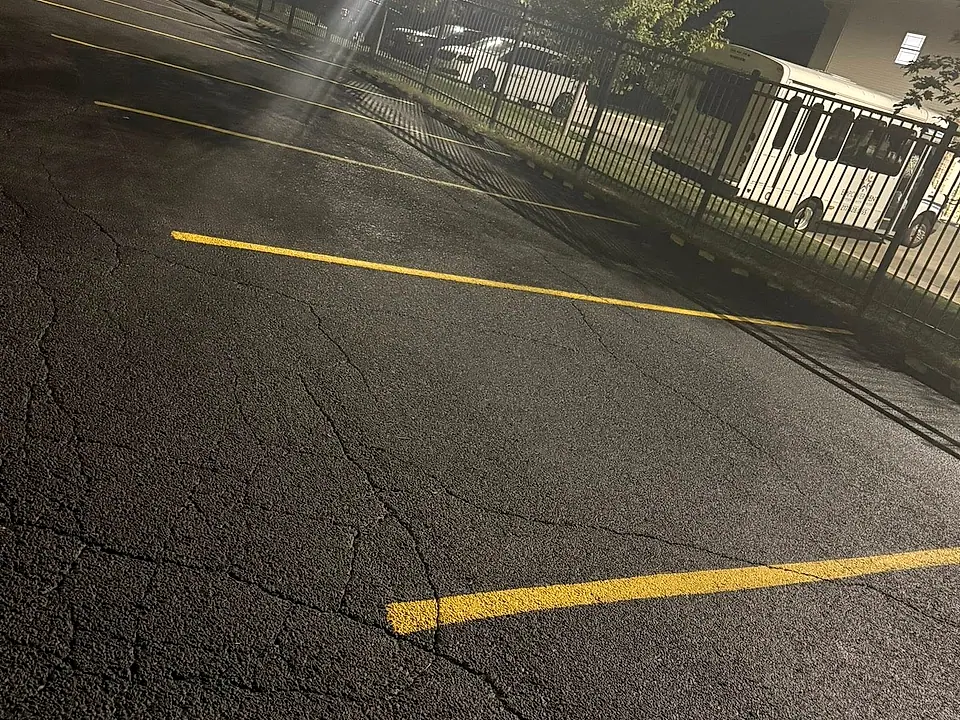 Crew laying down bright yellow parking-lot stripes after dark, work lights on