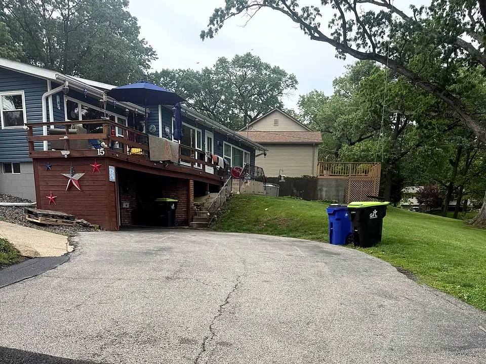 Fresh dark asphalt apron laid at the entrance of a residential driveway