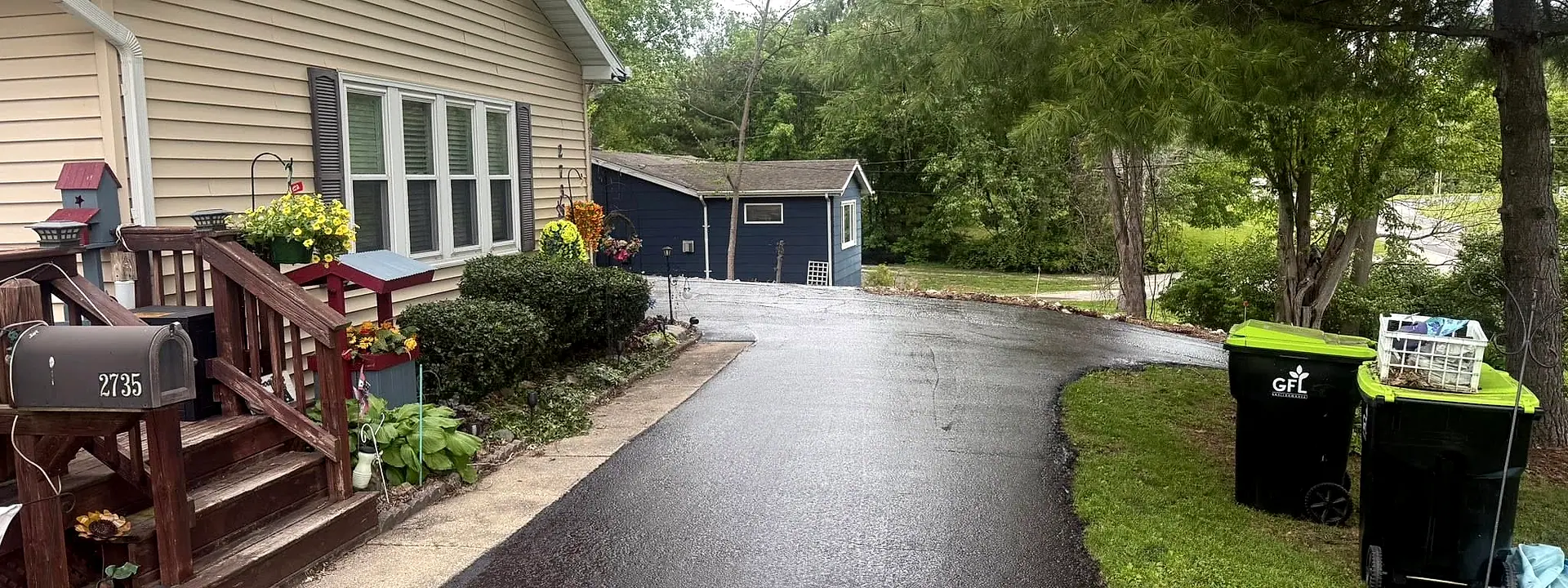 A wide, curving wet-black driveway after seal coating