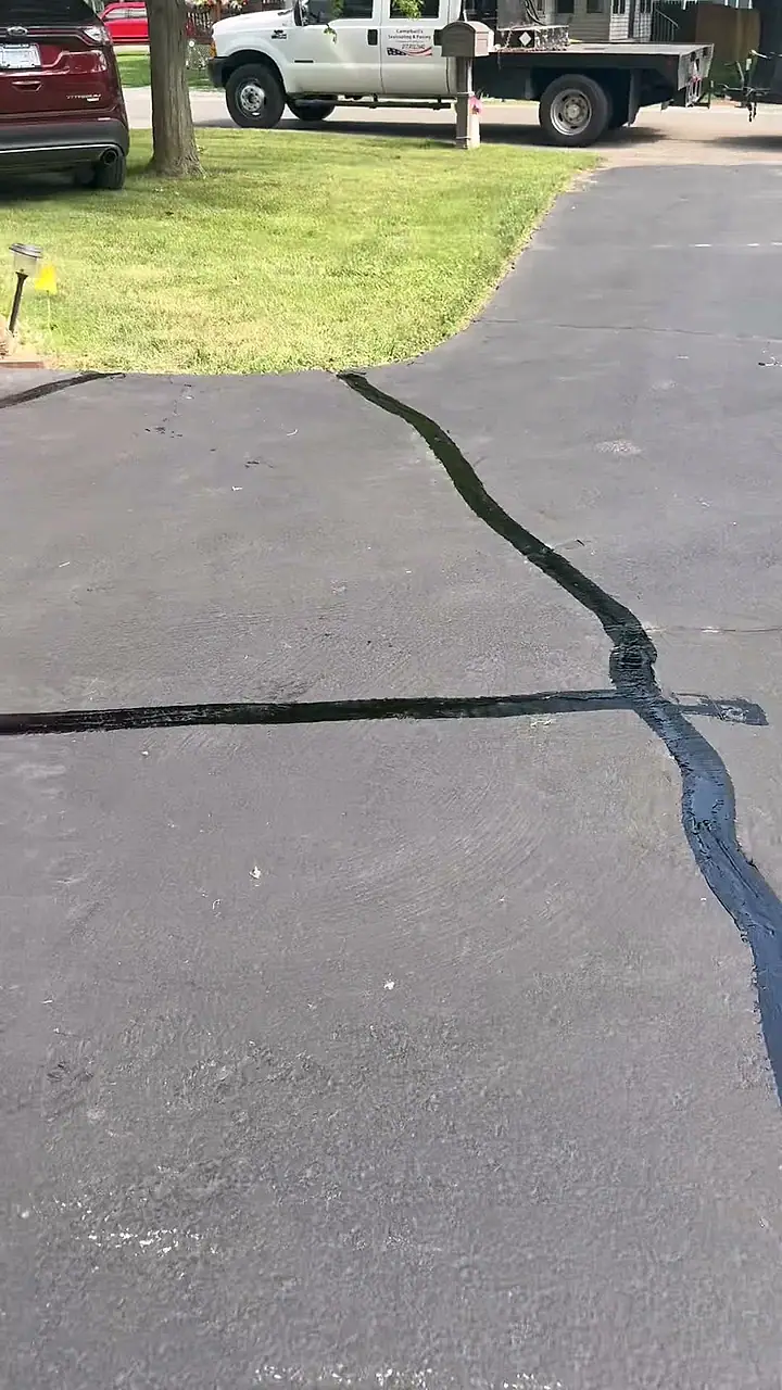 Slow pass down a freshly crack-filled and sealed driveway with the Campbell's truck at the curb