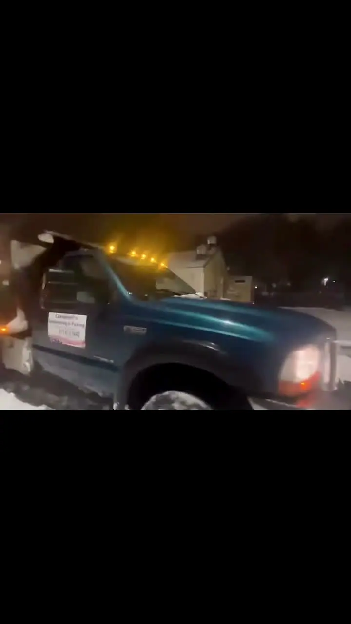Campbell's branded truck plowing a snow-covered lot at night